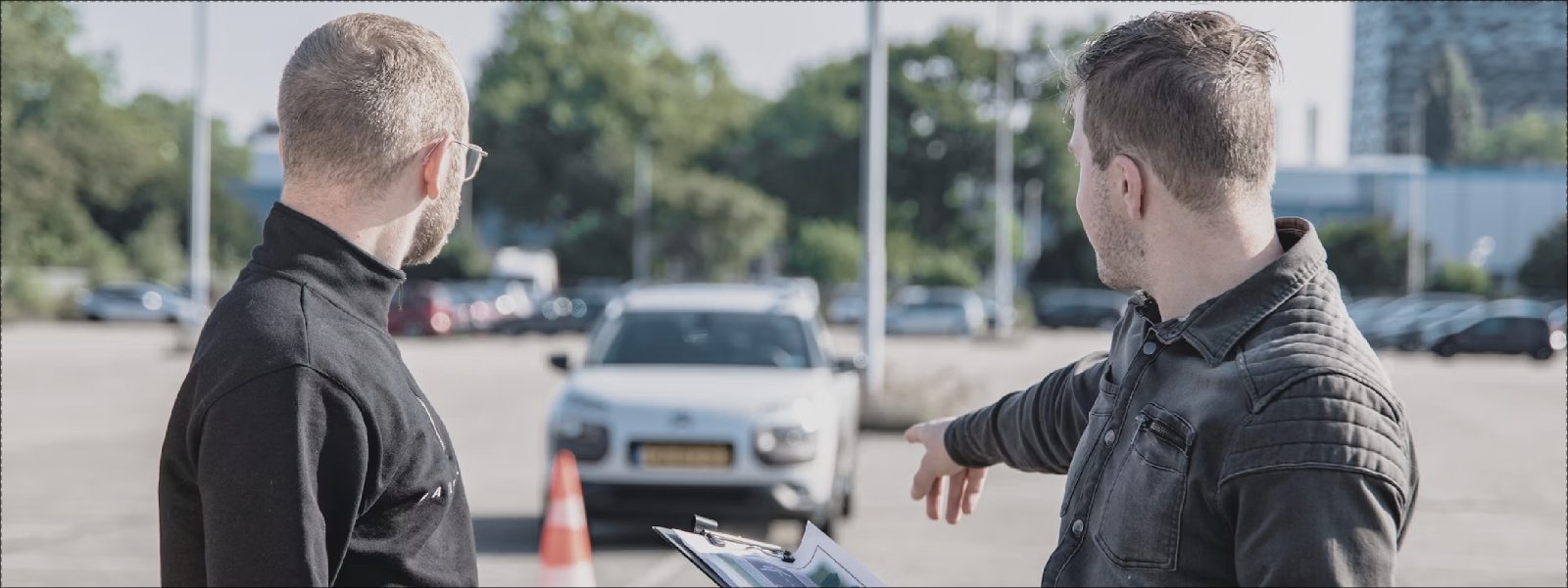 Un moniteur et un élève devant une voiture d'auto-école
